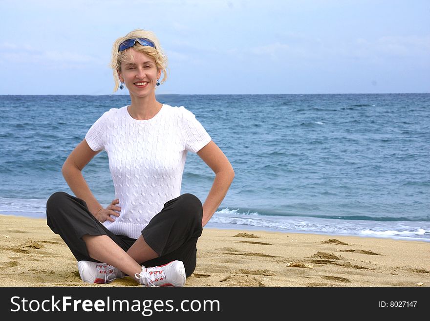 Blond girl meditating by the sea