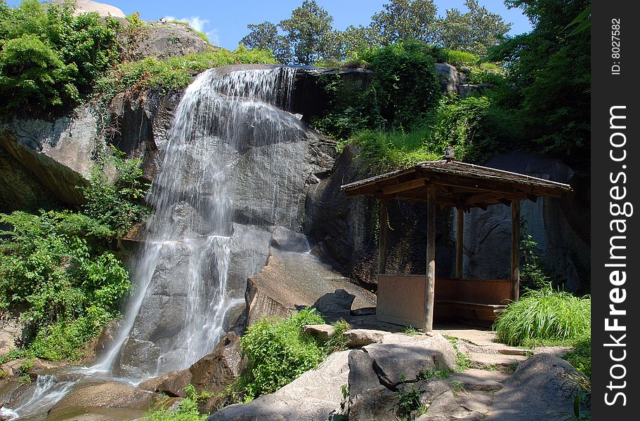 Waterfall next to a small oriental cabin/house. Waterfall next to a small oriental cabin/house.