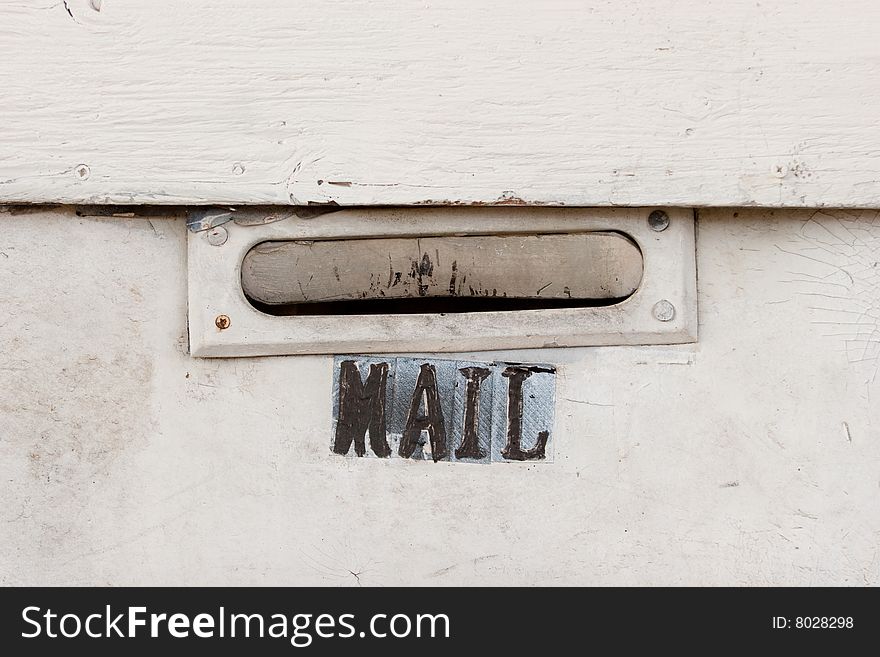 An old unused mail slot on a white wall.