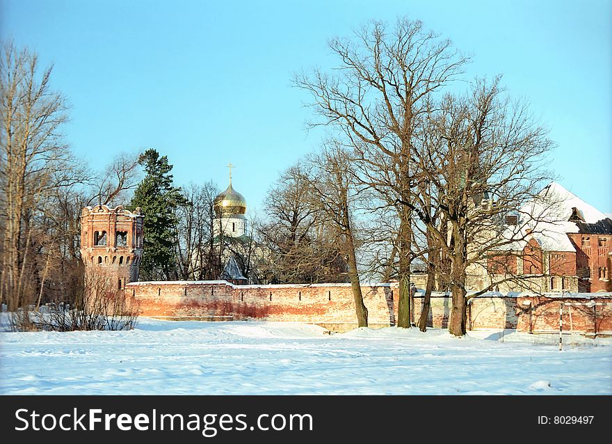 Red brick fortress wall and a church in winter. Red brick fortress wall and a church in winter