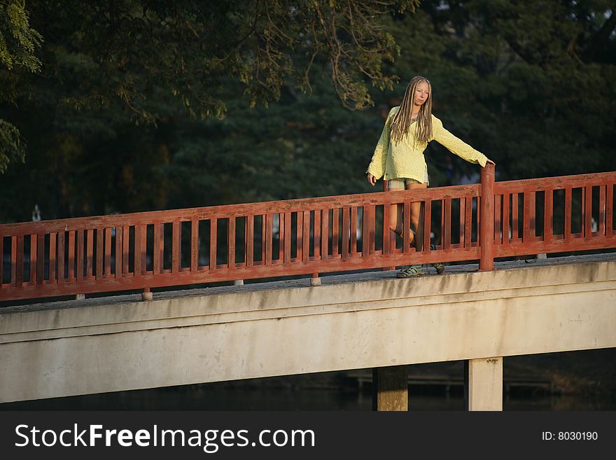 Girl in yellow blouse on red bridge in the park. Girl in yellow blouse on red bridge in the park