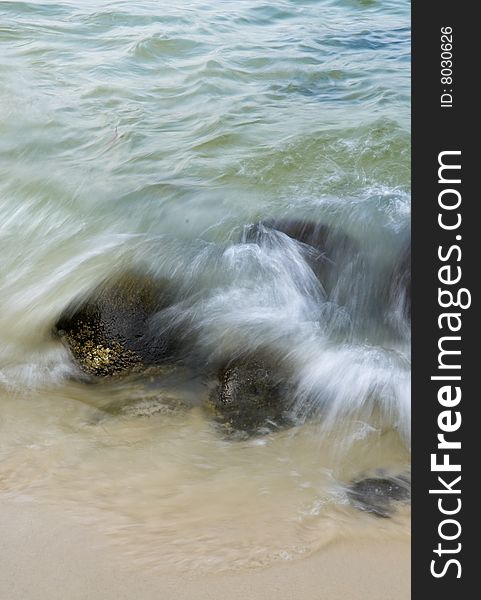 Wave crashing on rocks during the ebbing tide. Wave crashing on rocks during the ebbing tide