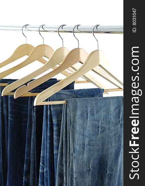 Blue jeans and trousers on wooden hangers