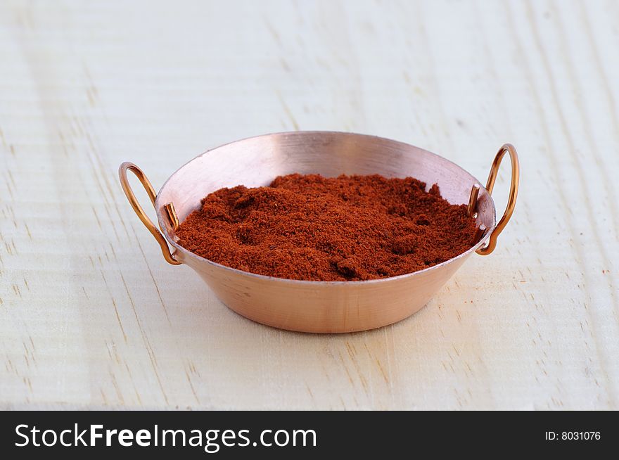 Picture of frying pan isolated in background of wood with paprika. Picture of frying pan isolated in background of wood with paprika