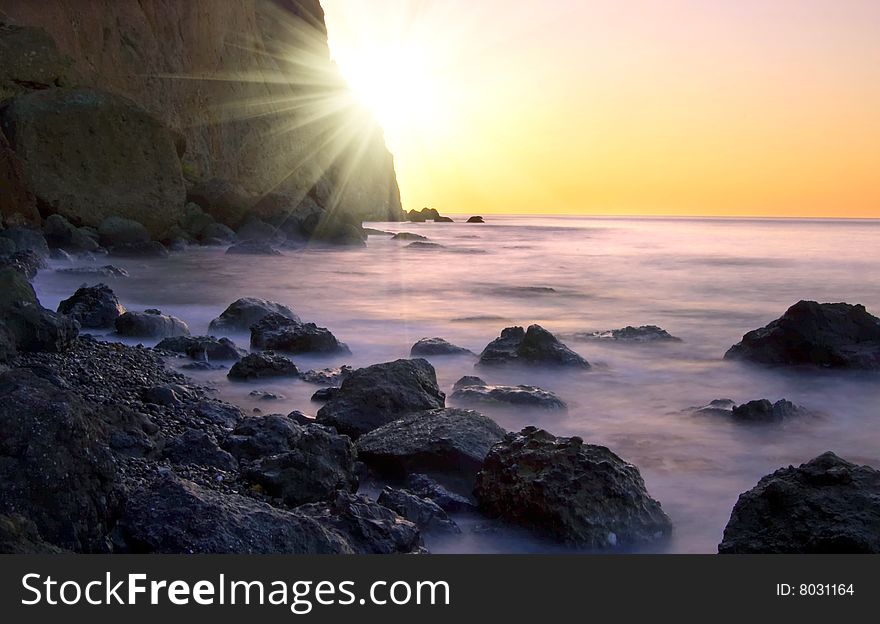 Sunrise at seaside with rock silhouette