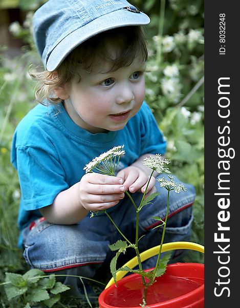 A boy in the garden with flower and red bucket
