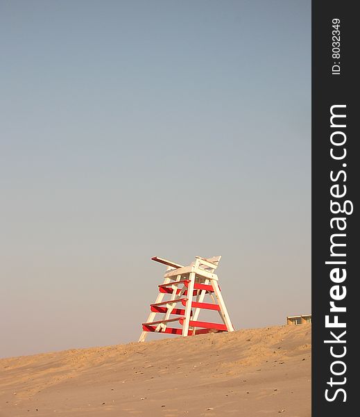 Red and white striped lifeguard stand high up on a sandy dune in the early morning sun Cape May beach. Red and white striped lifeguard stand high up on a sandy dune in the early morning sun Cape May beach