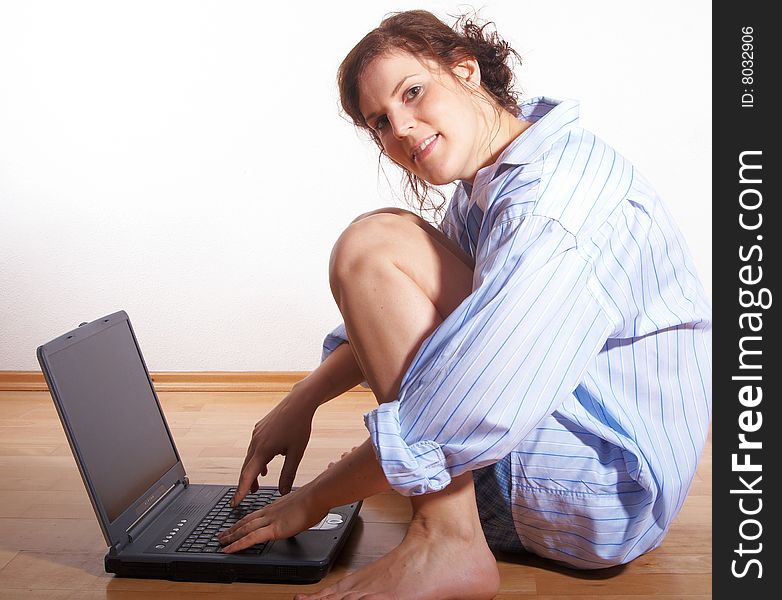 A young woman at home with her laptop sitting on the floor. A young woman at home with her laptop sitting on the floor.