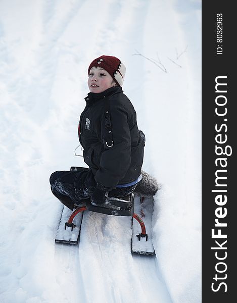 A boy in red hat on the sledge. A boy in red hat on the sledge