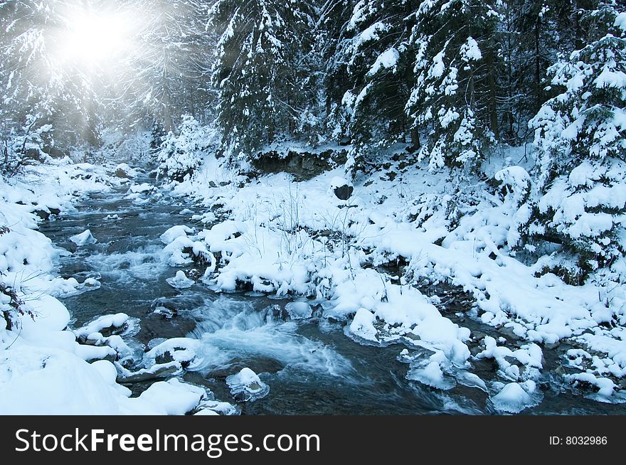 Winter landscape with stream and bright sun