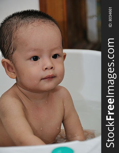 Naked baby is sitting in white bathtubs and smile to his Mom. Naked baby is sitting in white bathtubs and smile to his Mom.