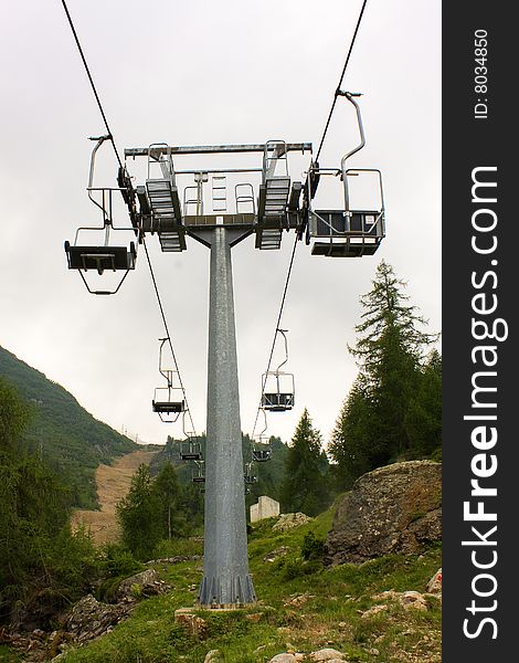 Empty chairlift between woods and rocks. Empty chairlift between woods and rocks