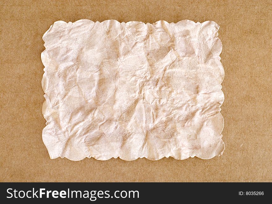 Old rectangle crumpled brown paper, with cut scalloped edges, isolated with cardboard border, copy space. Old rectangle crumpled brown paper, with cut scalloped edges, isolated with cardboard border, copy space