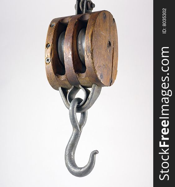 Antique block and tackle for hoisting heavy objects. Twin pulleys with a metal hook on the bottom and a circular ring at the top.