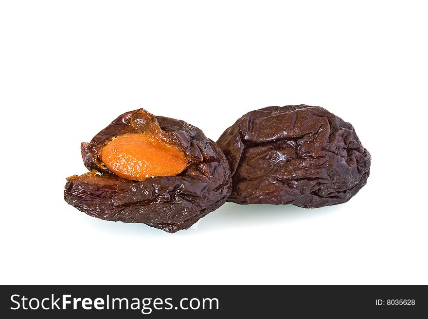 Close-up of two dried prunes or plums one open with stone showing against a white background