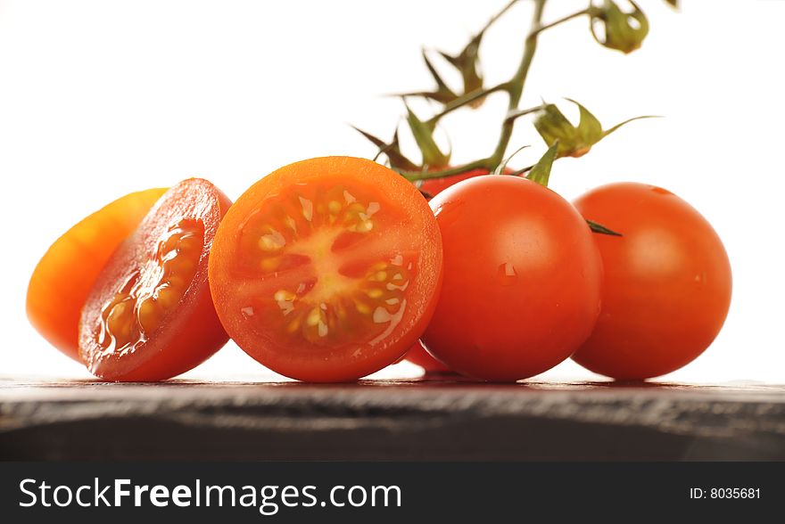 Group of fresh Cherry Tomatoes, some sliced, some whole on a black surface