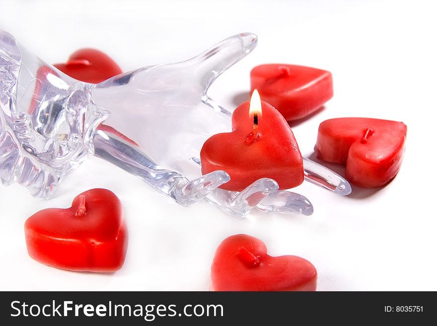 Red heart shaped candle and glass or ice hand holding a burning candle (Fragility of Love concept)