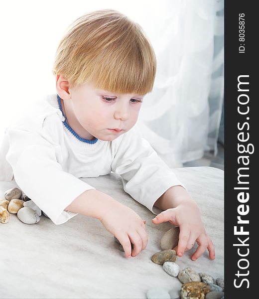 The serious little boy holds sea stones