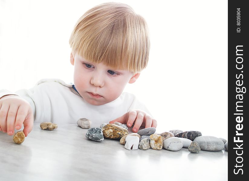 The serious little boy holds sea stones