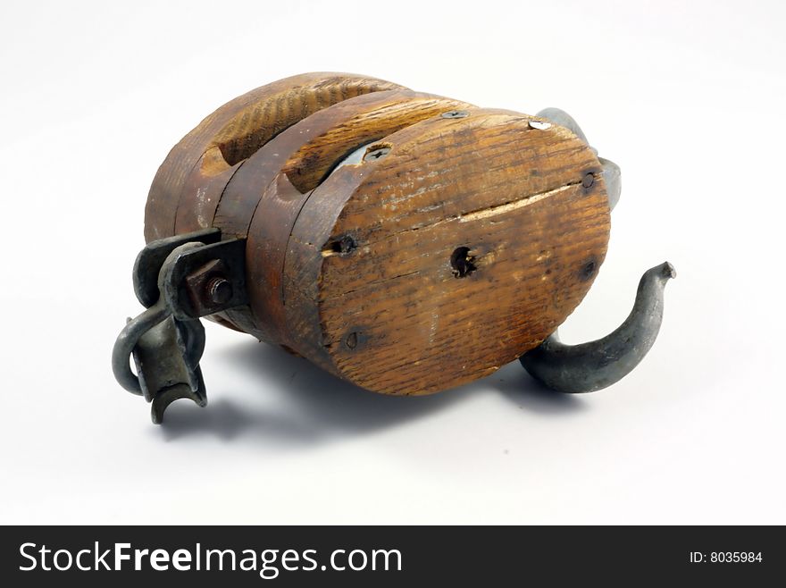 Antique block and tackle for hoisting heavy objects.  Twin pulleys with a metal hook on the bottom and a circular ring at the top.