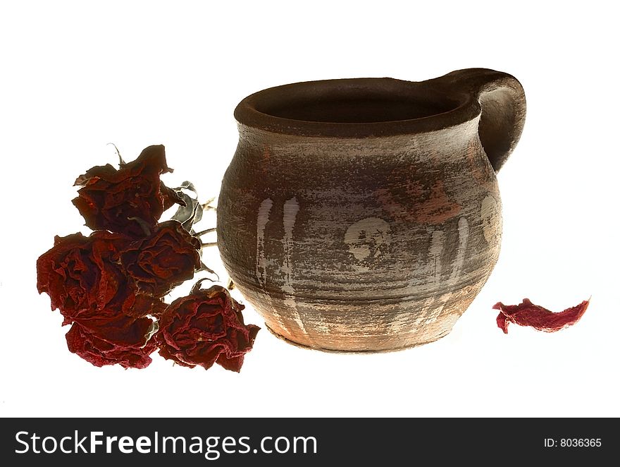 Clay cup with dry roses on a white background