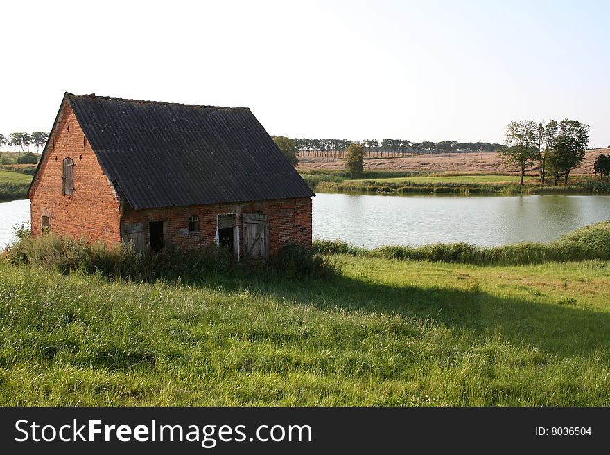 An old barn with fields and lake in the background