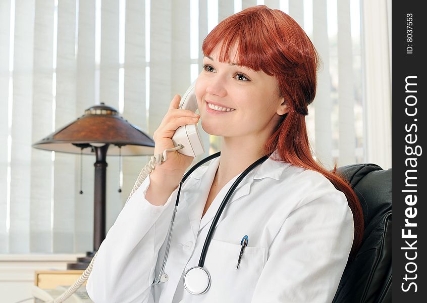 Young female doctor calling on phone, smiling.