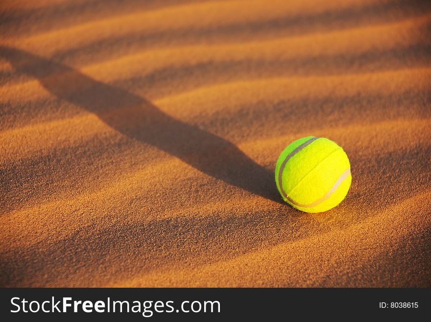 A yellow tennis ball in desert sand. A yellow tennis ball in desert sand