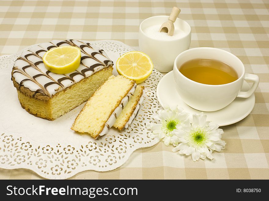 Lemon cake setup - an afternoon tea theme - sweet food - lemon cake, sugar, lemons and flowers in beige and pink - coziness.