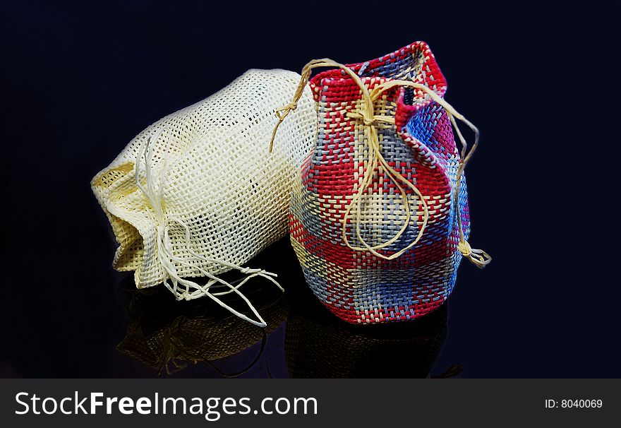 Pair of traditional country styled gift bags on black glassy background. Low key lighting. Pair of traditional country styled gift bags on black glassy background. Low key lighting.