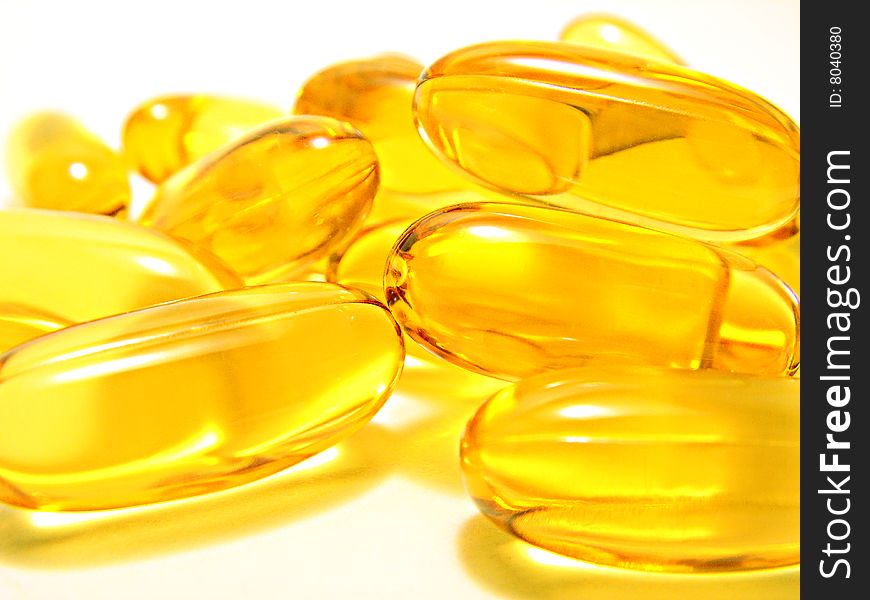 Yellow transparent capsules over a white background. Yellow transparent capsules over a white background