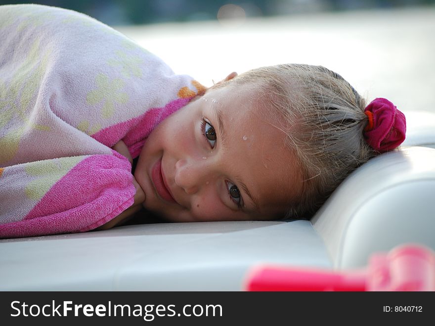 A beautiful little girl dries off and relaxes after a long day of swimming at the beach. A beautiful little girl dries off and relaxes after a long day of swimming at the beach