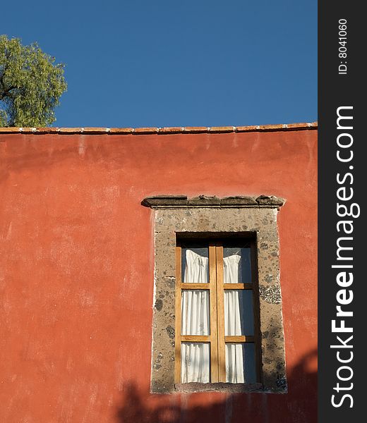 Mexican window set in burnt sienna coloured wall of Mexican house, San Miguel de Allende, Mexico.