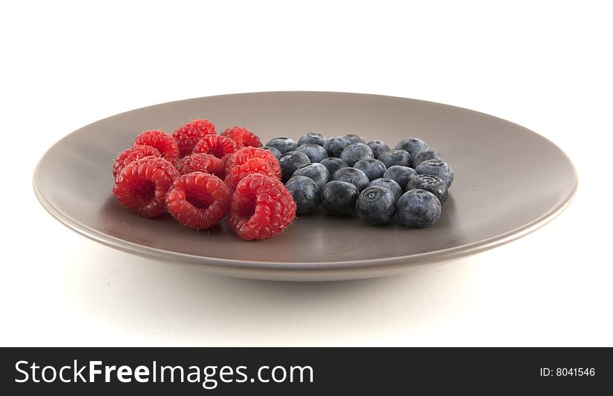 Close up of blueberries and raspberries on a plate. Shallow depth of field