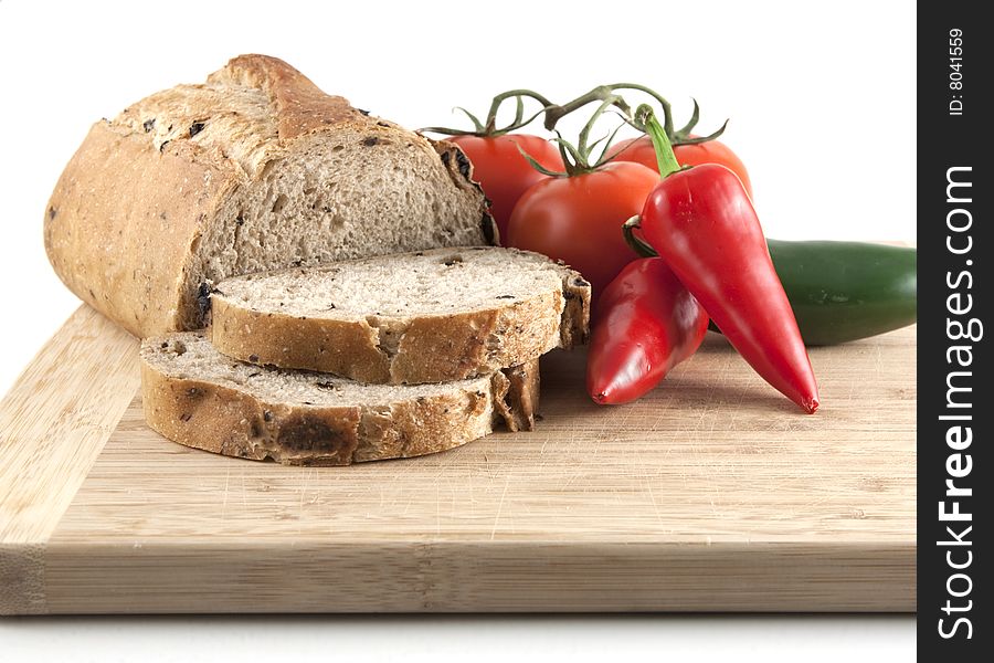 Close up of sliced olive bread with tomatoes and peppers on a cutting board. Close up of sliced olive bread with tomatoes and peppers on a cutting board.