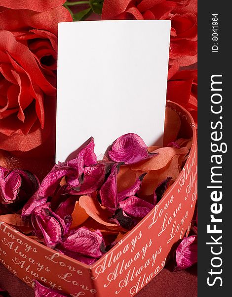 Heart shaped gift box with some roses over it and white note. Heart shaped gift box with some roses over it and white note