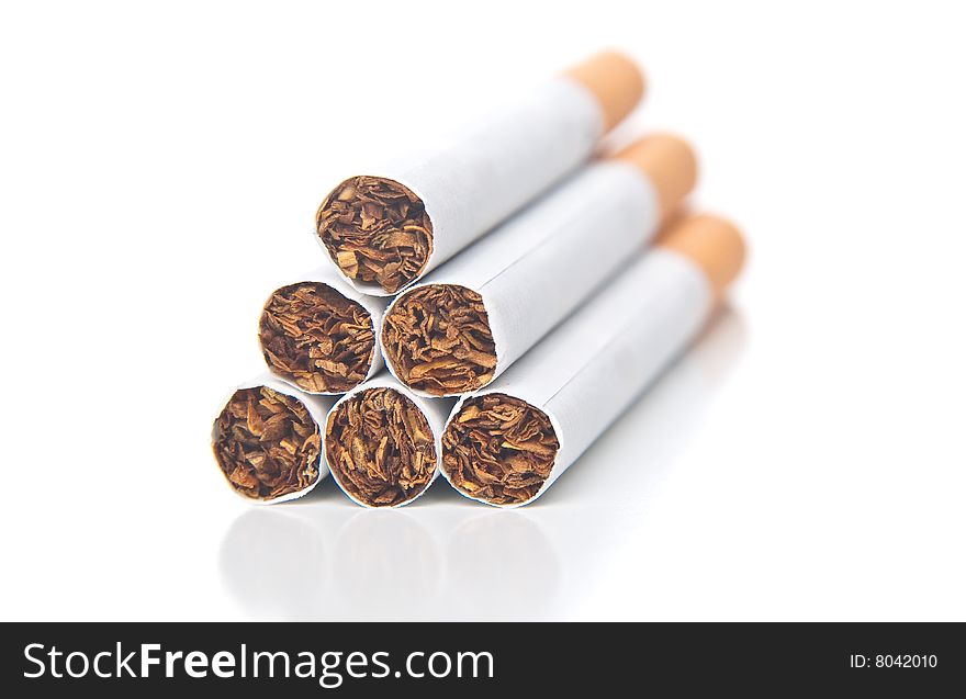 Isolated pyramid of cigarettes laying on white