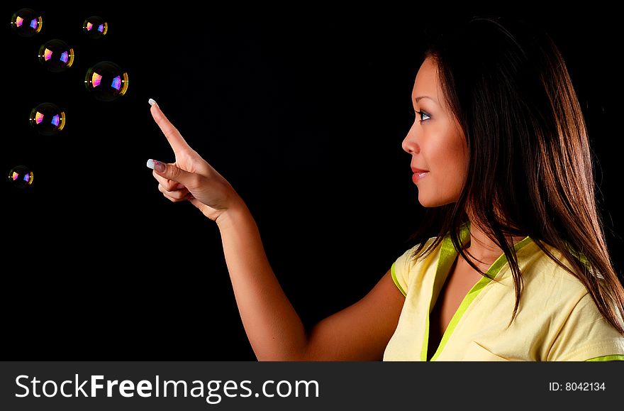 Beautiful young woman witn soap bubbles at black background