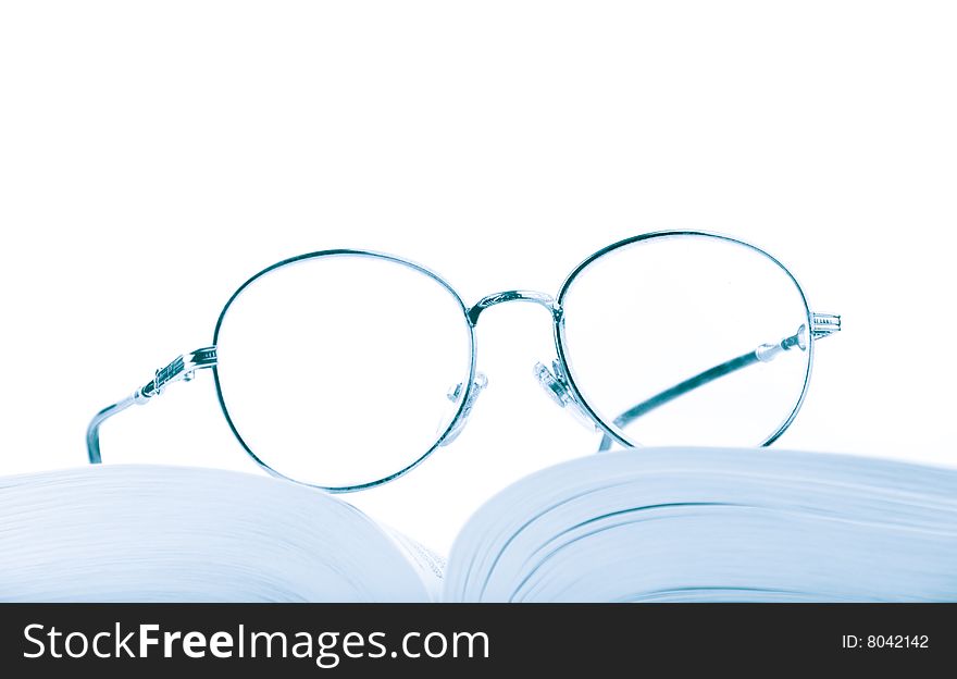 Glasses on the open book in blue tones