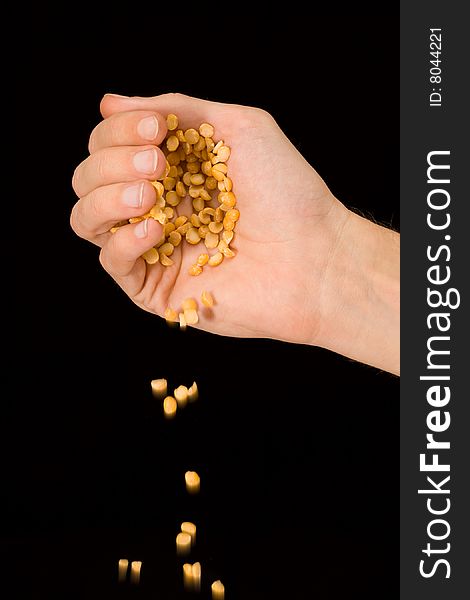 Man's hand pouring split peas isolated on black background