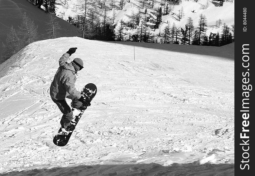 Snowboarder jumping down on the slope