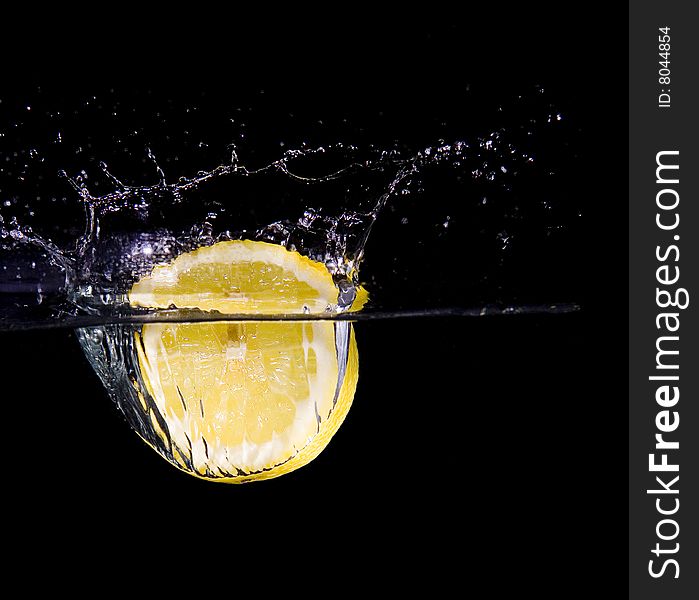 Lemon slice in water with bubbles on black ground. Lemon slice in water with bubbles on black ground