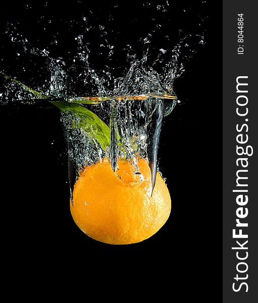 Tangerine in water with bubbles on black ground. Tangerine in water with bubbles on black ground