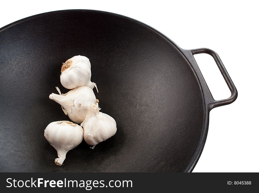 Four garlic bulbs in a black cast iron wok. Four garlic bulbs in a black cast iron wok