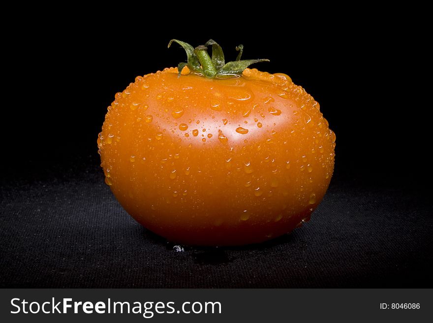 Tomato single with drops on black not isolated background