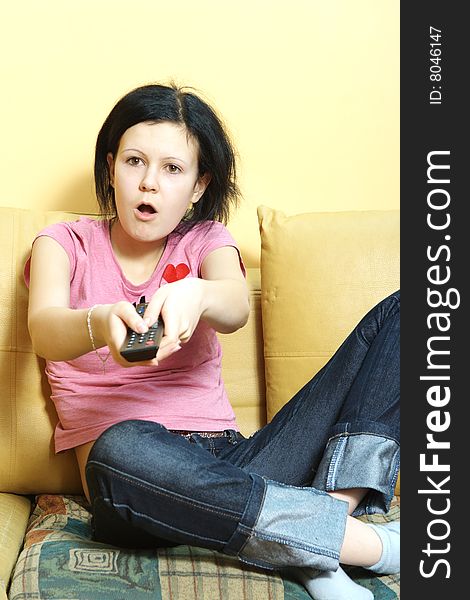 Female in blue jeans sitting on the sofa and watching TV