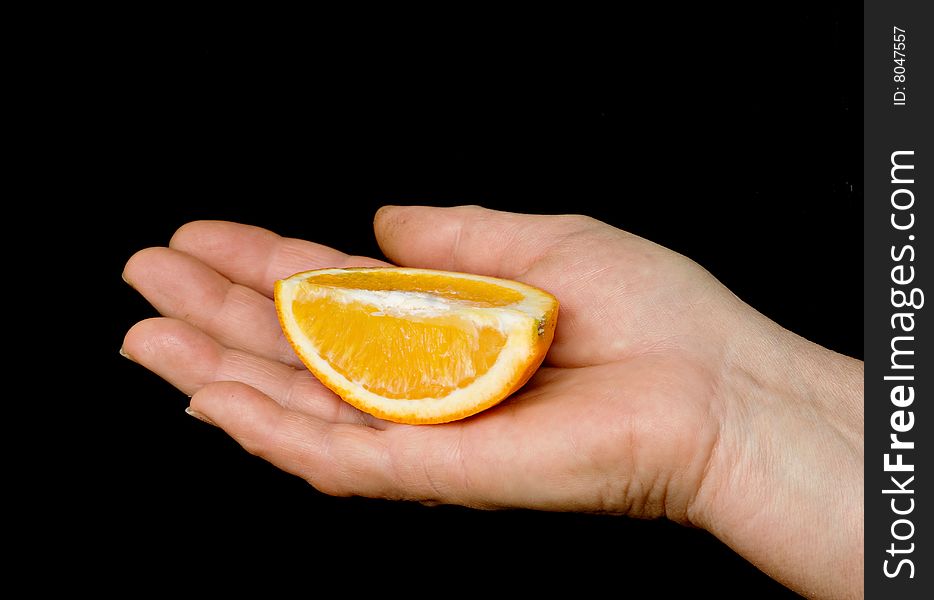 Hand with an orange slice isolated on black background