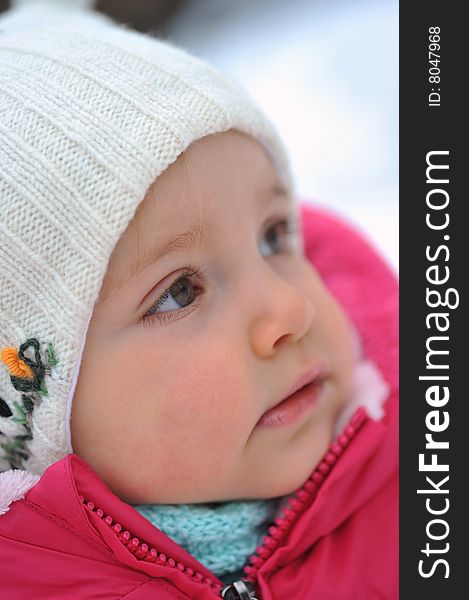 Little girl in white hat in  winter