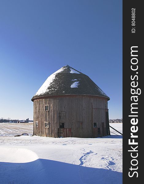 A single round barn sits in a field of snow. A single round barn sits in a field of snow.