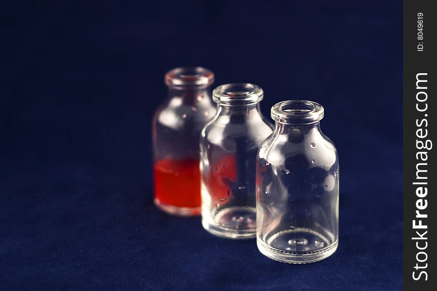 Three vials: two empty and one with red medicine